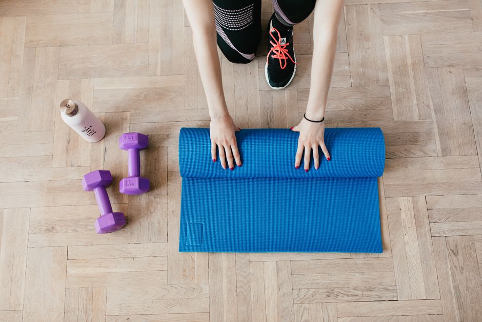 Woman performing a squat with a single kettlebell in a clear, organized corner of a small room, highlighting efficient use of space for fitness.