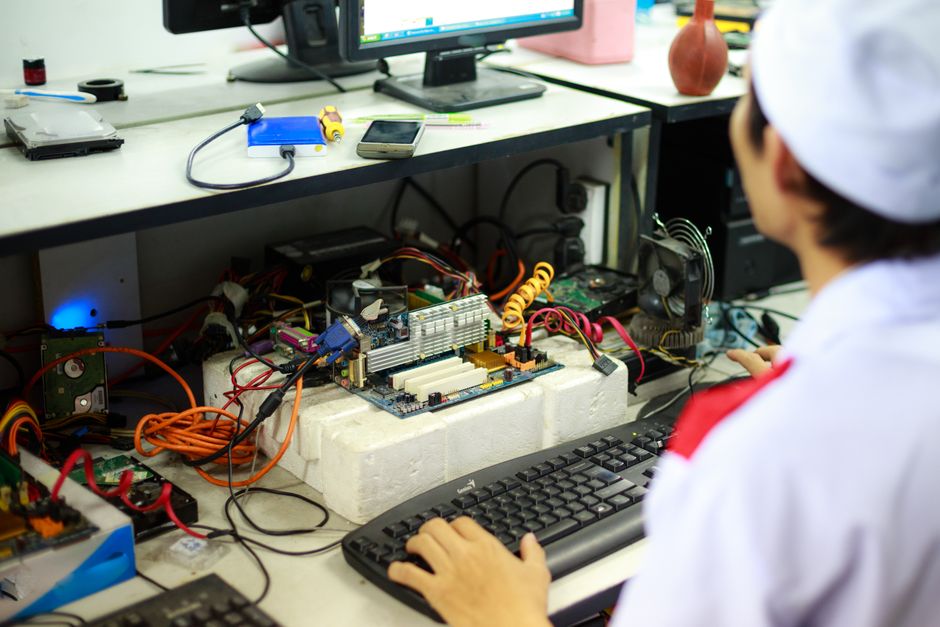 An adult person, possibly a parent, thoughtfully examining computer components like a graphics card or processor.