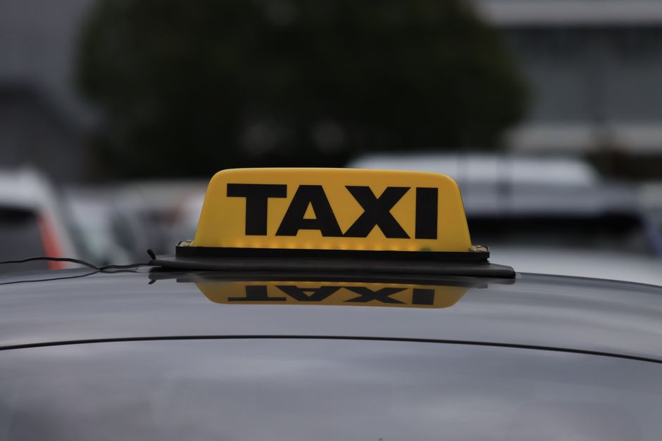 A line of official white taxis waiting at a designated airport taxi stand at dusk.