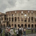 A wide shot of the ancient Roman Colosseum bustling with tourists, representing historical travel in Europe.