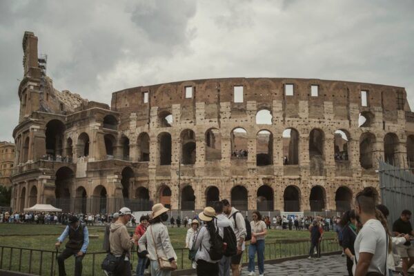 A wide shot of the ancient Roman Colosseum bustling with tourists, representing historical travel in Europe.