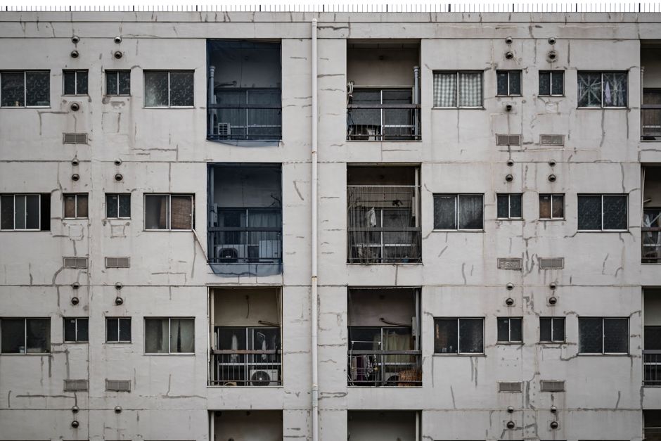 A person holding a smartphone showing a Wi-Fi signal strength app in an apartment with a visible thick concrete wall.
