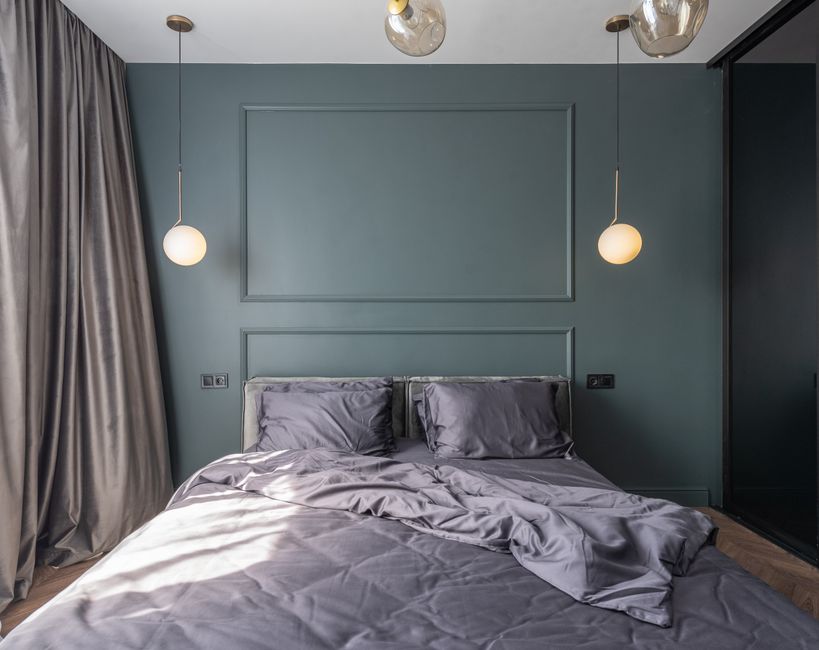 A cluttered bedroom nightstand overflowing with electronics, books, and miscellaneous items, illustrating common mistakes in bedroom design.