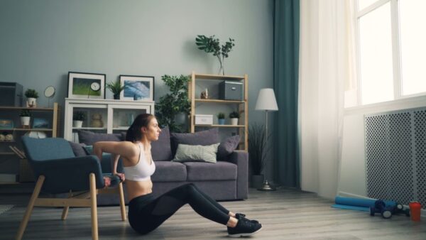 Woman performing bodyweight squats in a bright living room, illustrating home workout simplicity for beginners.