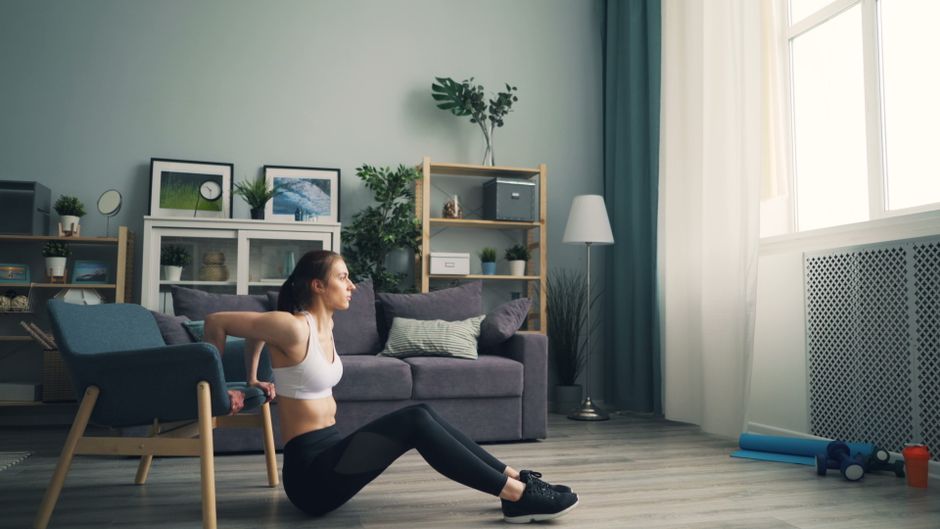 Woman performing bodyweight squats in a bright living room, illustrating home workout simplicity for beginners.