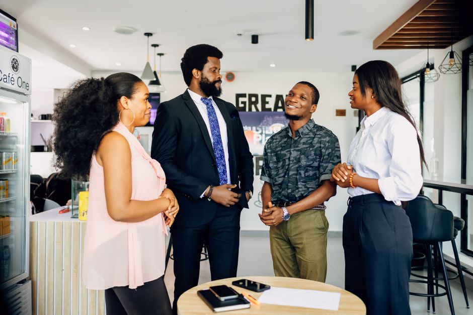 A diverse group of professionals in a modern office, dressed in various business casual outfits, discussing a project.