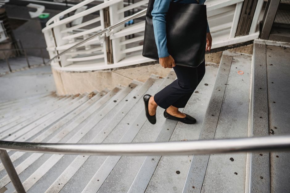 A working professional in a sophisticated city environment, carrying a structured leather handbag and wearing an elegant watch, epitomizing practical fashion accessories.