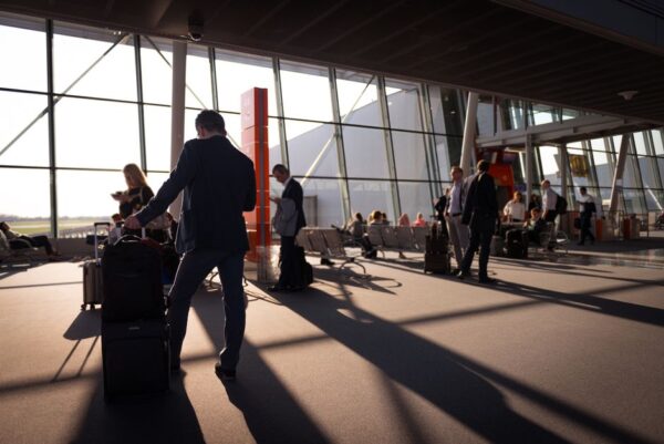 Woman smartly dressed in a blazer and trousers, carrying a sleek carry-on suitcase through an airport terminal, looking confident and ready for a business trip.