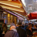 A bustling European street market with fresh produce, cheese, and flowers, showcasing local life.