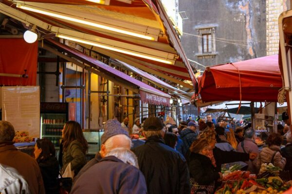 A bustling European street market with fresh produce, cheese, and flowers, showcasing local life.