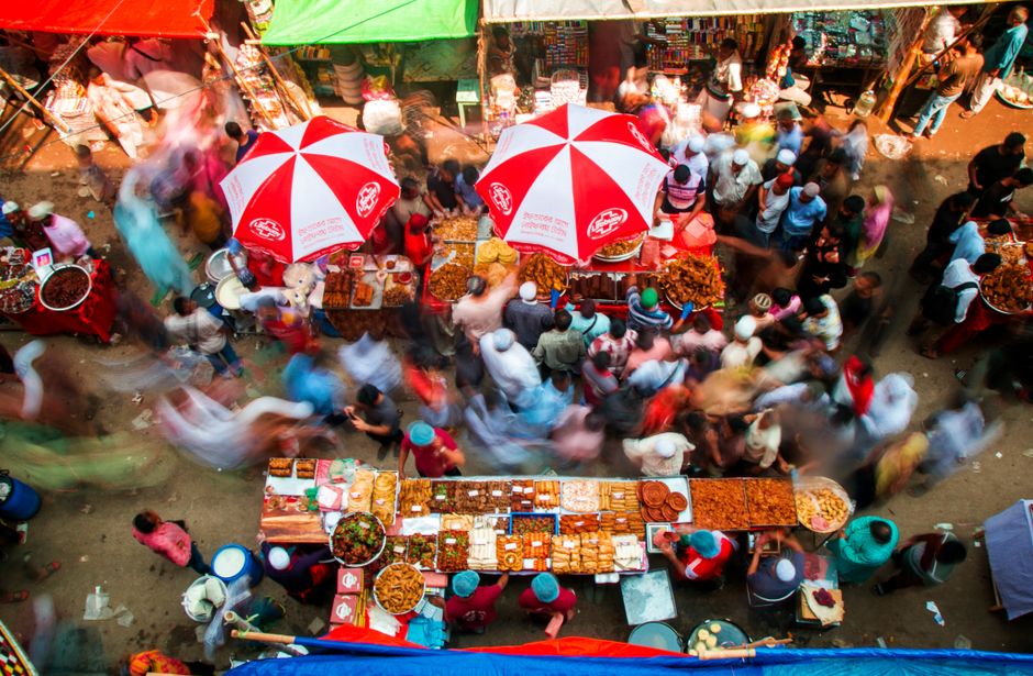 A vibrant street food market in a diverse city, showing various stalls selling local delicacies and people interacting, representing authentic culinary experiences.