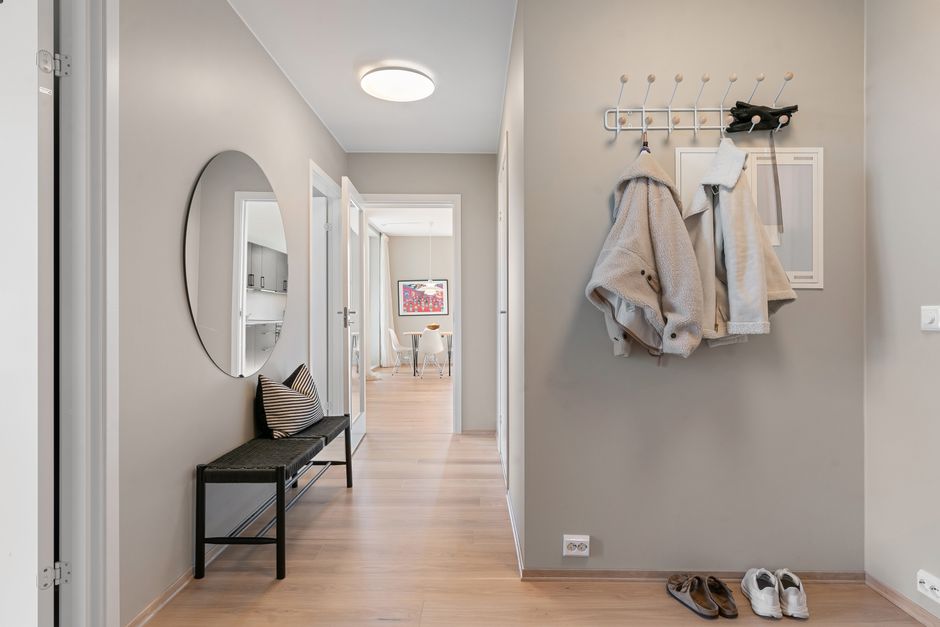 A minimalist small entryway with a white storage bench, a few tasteful coat hooks, and a vertical shoe rack, radiating calm.
