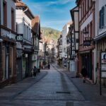 A narrow, cobblestone street in a historic European small town, lined with colorful buildings and flower boxes, suggesting a peaceful cultural experience.