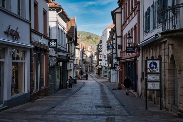 A narrow, cobblestone street in a historic European small town, lined with colorful buildings and flower boxes, suggesting a peaceful cultural experience.