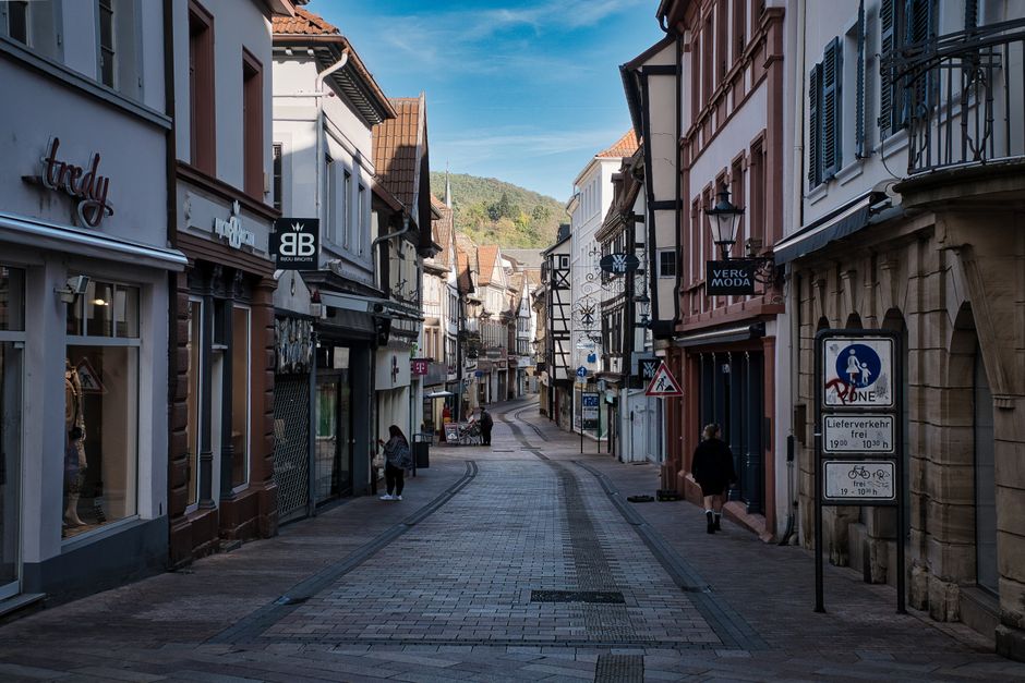 A narrow, cobblestone street in a historic European small town, lined with colorful buildings and flower boxes, suggesting a peaceful cultural experience.