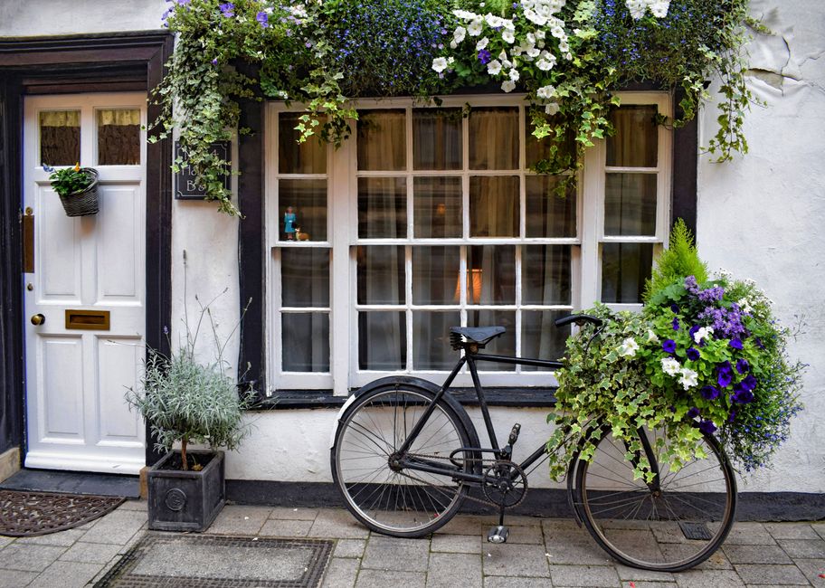 A charming, old-world guesthouse building with colorful flowers adorning its windows and a welcoming entrance.