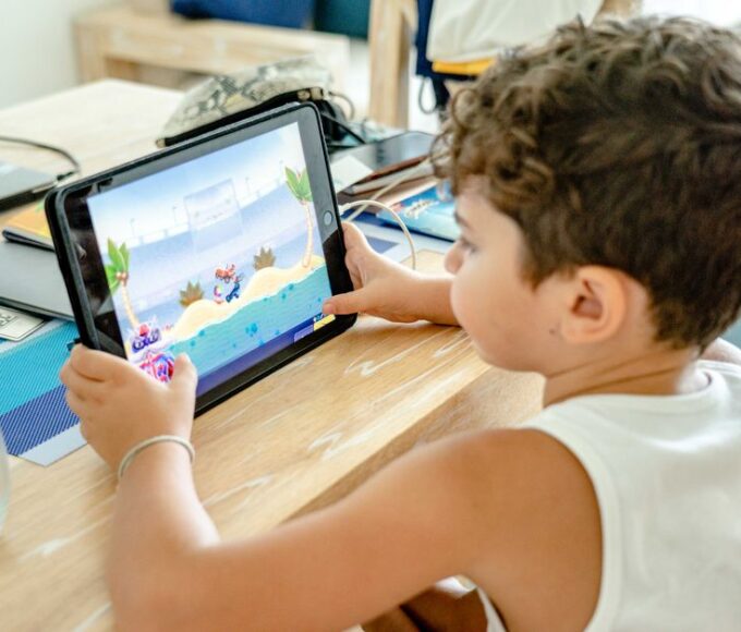 A family, including a child and two parents, engaging with an educational game on a tablet, fostering interactive learning.