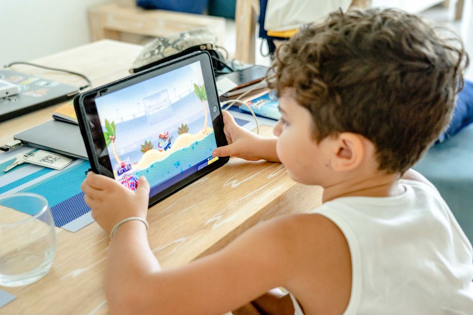 A family, including a child and two parents, engaging with an educational game on a tablet, fostering interactive learning.