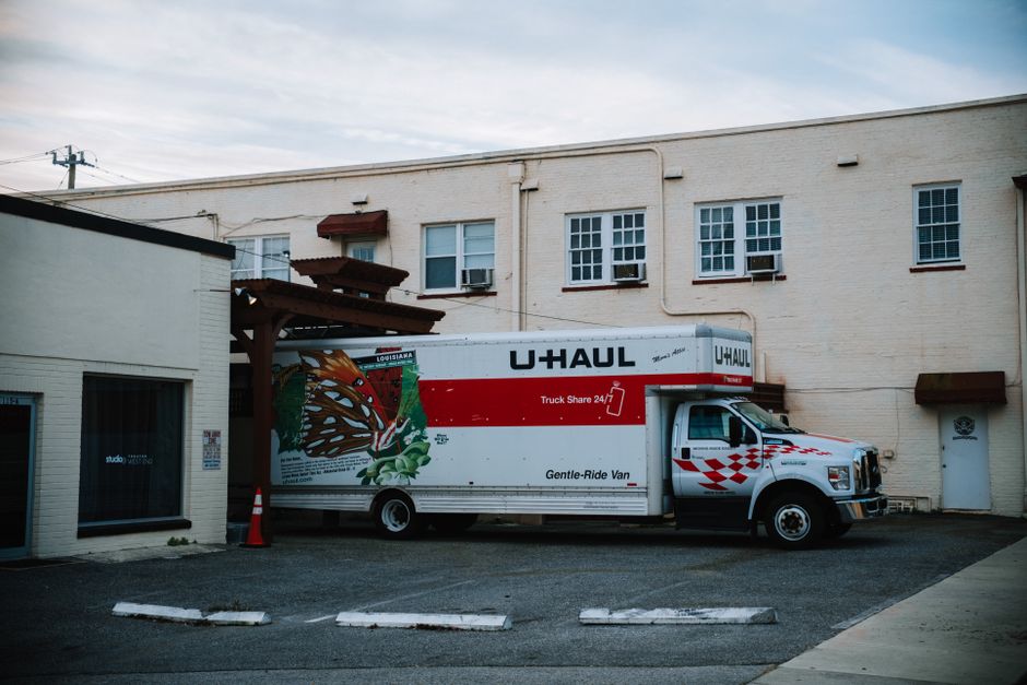 A moving truck parked on a busy city street in front of apartment buildings.