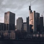 A person looking stressed amidst a backdrop of blurred city lights and tall buildings, symbolizing financial pressures in urban environments.