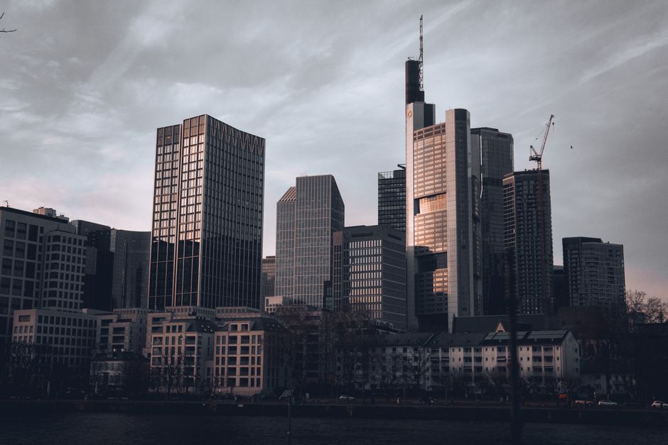 A person looking stressed amidst a backdrop of blurred city lights and tall buildings, symbolizing financial pressures in urban environments.