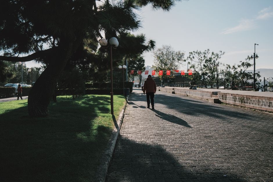 A person walking briskly through a sunny city street, enjoying the morning light, with historic buildings in the background.