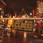 A small cafe or boutique with a 'Closed for Holiday' sign on its door, lights off, emphasizing unexpected closures.