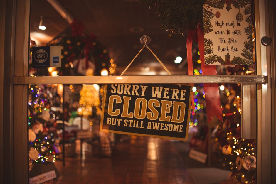 A small cafe or boutique with a 'Closed for Holiday' sign on its door, lights off, emphasizing unexpected closures.