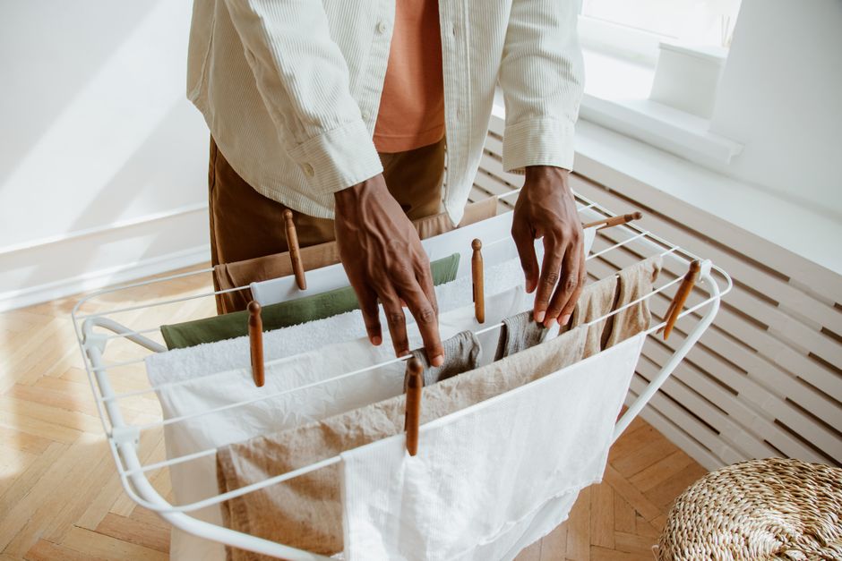 Stylish wooden drying rack with various garments air-drying in a minimalist living space, showcasing eco-friendly practices.