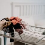 Clothes neatly piled on a bed during a wardrobe reset, illustrating the initial decluttering step.