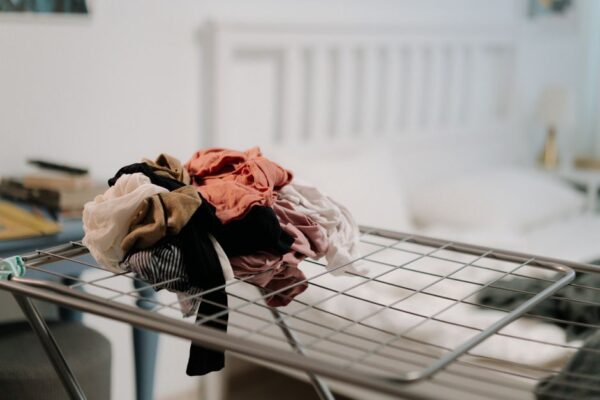 Clothes neatly piled on a bed during a wardrobe reset, illustrating the initial decluttering step.
