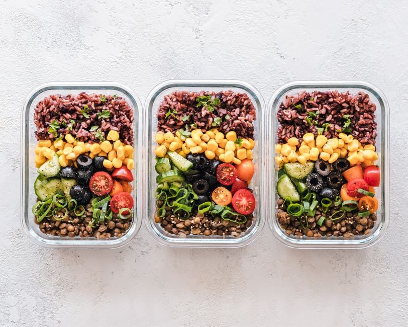 A variety of vibrant, healthy meals portioned into clear glass containers, showcasing different cuisines and ingredients for a week of diverse eating without repetition.