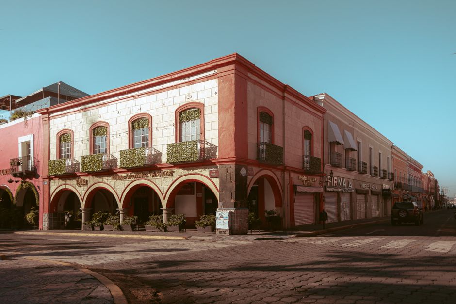 A vibrant, bustling plaza in a colonial Mexican town, with people relaxing at outdoor cafes and admiring the ornate architecture, highlighting local life.