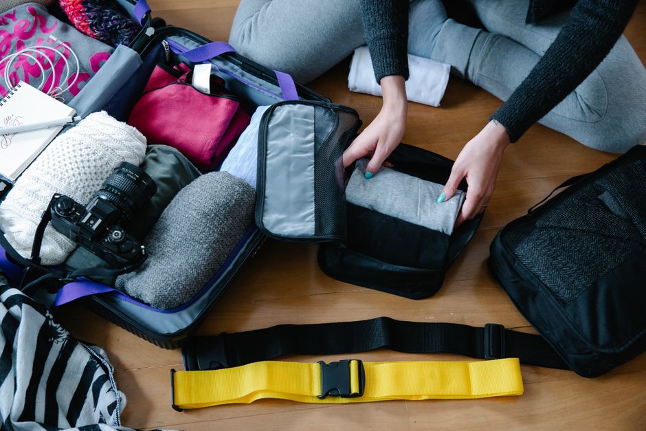 Several open packing cubes in different sizes, neatly filled with rolled clothing items, sitting inside a half-packed travel bag.
