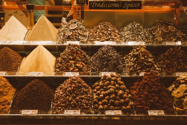 A vibrant, bustling spice stall at a market, with various colorful spices arranged in mounds, hinting at rich culinary traditions.