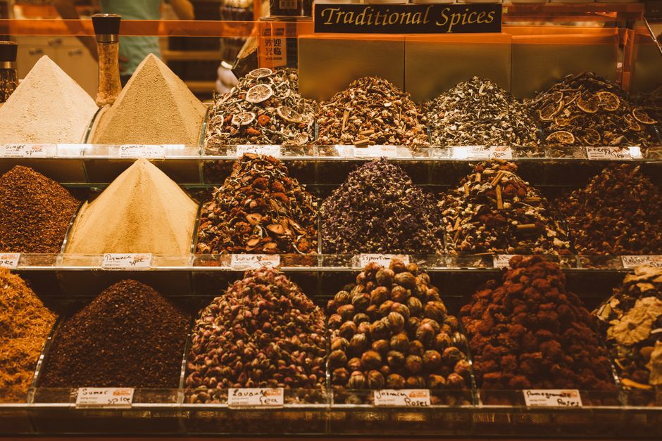 A vibrant, bustling spice stall at a market, with various colorful spices arranged in mounds, hinting at rich culinary traditions.