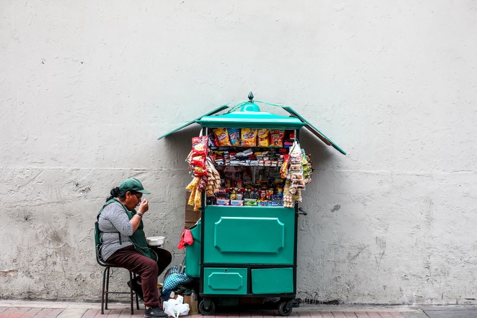 A vibrant street food stall in a bustling South American city, showcasing colorful fruits and local snacks, with local vendors interacting with customers.