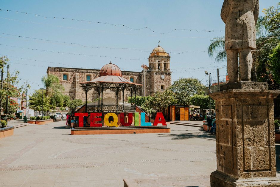 A vibrant, uncrowded town square in San Miguel de Allende, Mexico, with colorful colonial buildings and people relaxing at outdoor cafes.