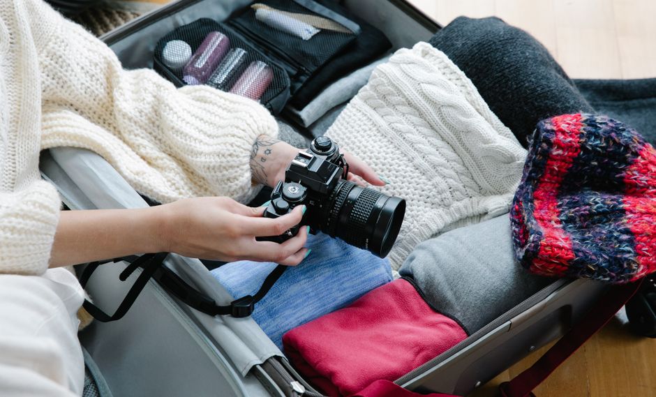 A flat lay showing essential red-eye flight comfort items: a neck pillow, eye mask, noise-canceling headphones, and a reusable water bottle.