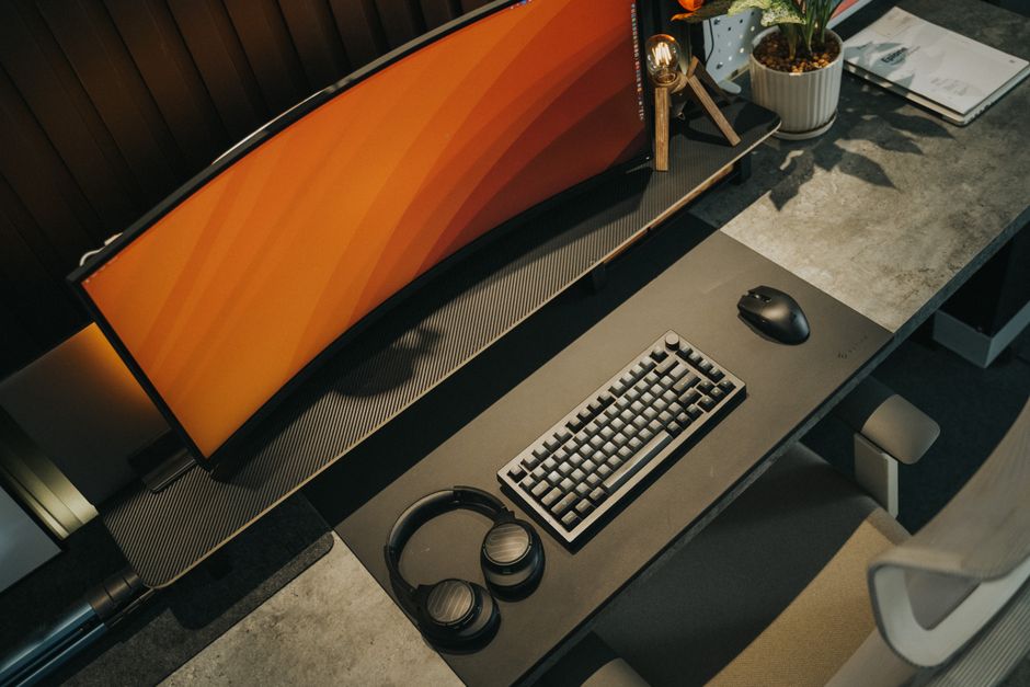 A clean, compact gaming setup in a small apartment corner, featuring a sleek monitor on a wall mount, a small form factor PC tucked neatly under the desk, and a simple ergonomic chair.