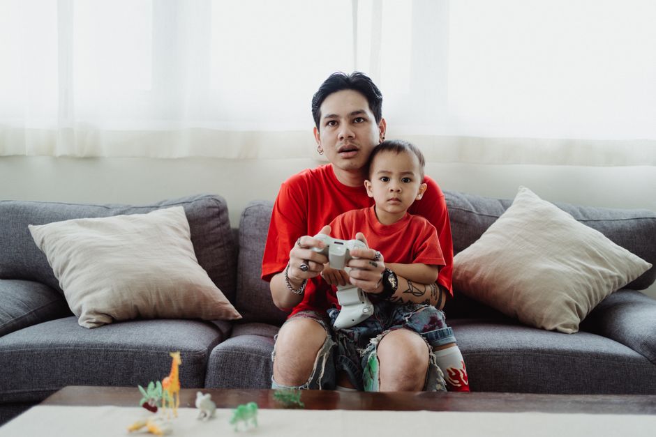 A parent with a thoughtful or slightly confused expression holding a video game box, with other games visible in the background, representing a purchasing decision.