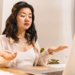 A person with a perplexed expression staring at a laptop screen displaying code, illustrating confusion from an AI hallucination.