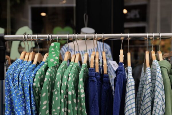 A bustling outdoor market stall in Copenhagen featuring various vintage clothing items, with people browsing.