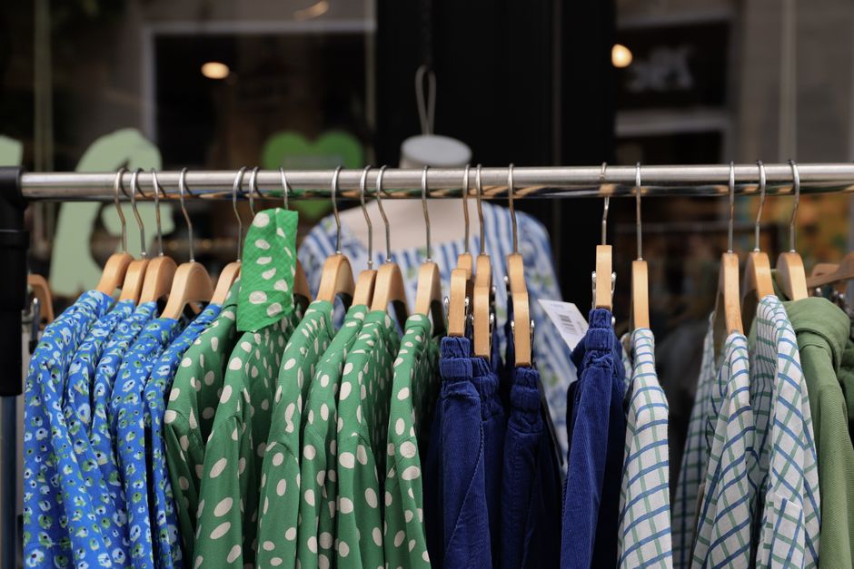 A bustling outdoor market stall in Copenhagen featuring various vintage clothing items, with people browsing.