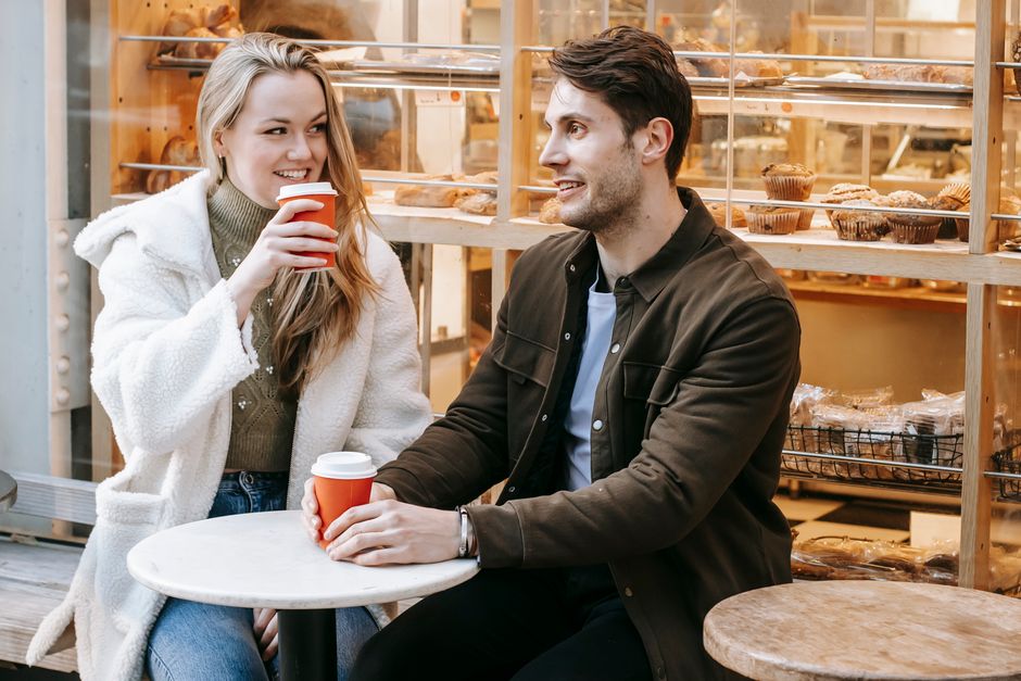 A couple enjoying a coffee at an outdoor cafe in Paris, with their bags on their laps, showcasing relaxed but aware travel.
