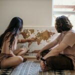 A couple looking at a large map of Europe spread on a table, highlighting potential routes for a multi-country trip.