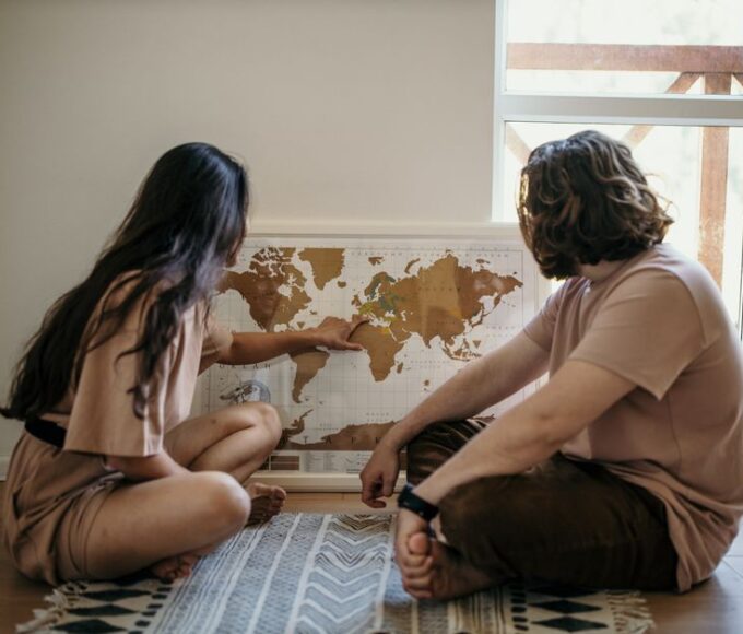 A couple looking at a large map of Europe spread on a table, highlighting potential routes for a multi-country trip.