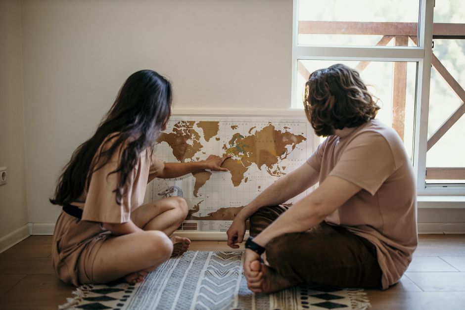 A couple looking at a large map of Europe spread on a table, highlighting potential routes for a multi-country trip.