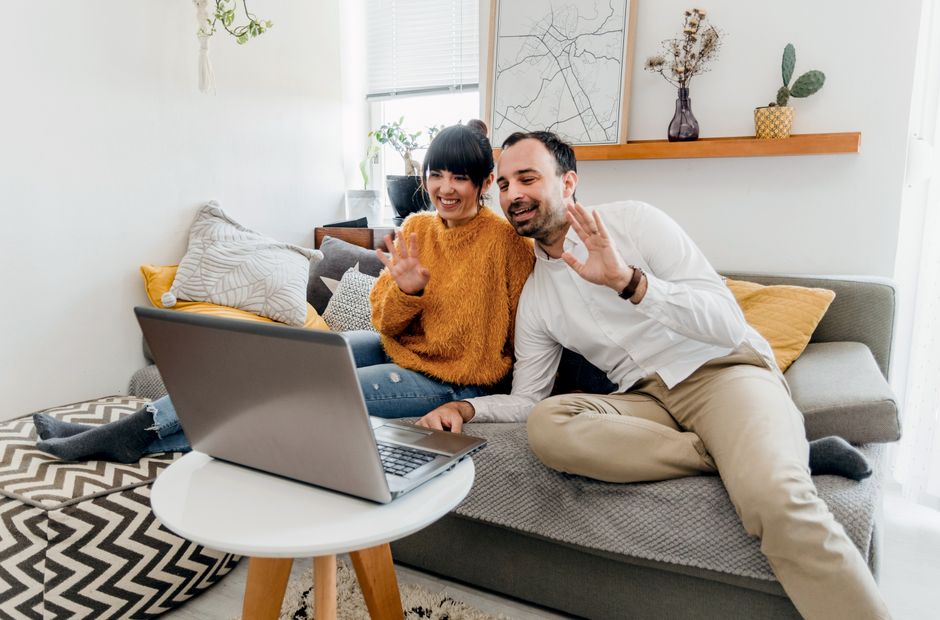 A couple on separate laptops, one in a city apartment, the other in a cozy home, having a video call with a split screen, symbolizing long-distance communication.