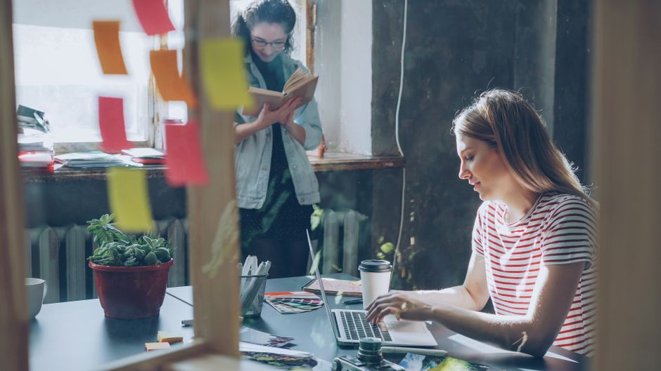 A creative professional at a desk, surrounded by notes and a digital tablet, carefully refining AI-generated content to match their unique voice.